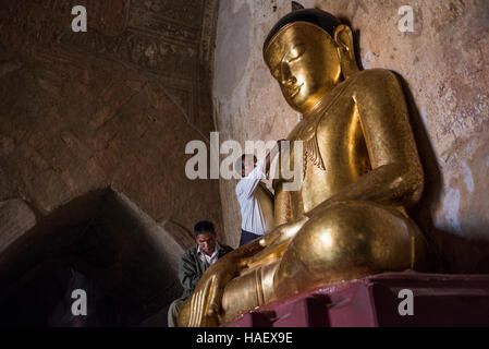 Persone che diano alle offerte di un Golden statua del Buddha presso il Tempio Sulamani a Bagan, Myanmar. Foto Stock