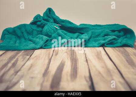 Verde di stoffa a maglia posa su un tavolo di legno, annata calda Foto Stock