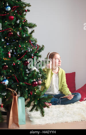 Ragazza giovane ascoltando i canti natalizi attraverso le sue cuffie al mattino presto Foto Stock