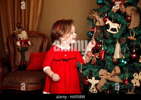 Ragazza permanente decorazioni mette a un albero di Natale. Ind verticale Foto Stock