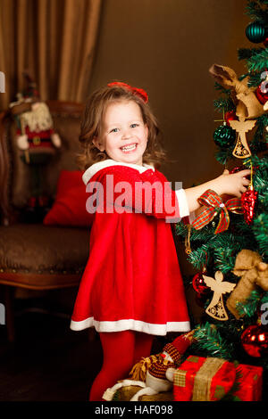 Ragazza permanente decorazioni mette a un albero di Natale. Ind verticale Foto Stock