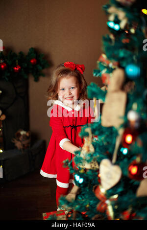 Ragazza permanente decorazioni mette a un albero di Natale. Ind verticale Foto Stock