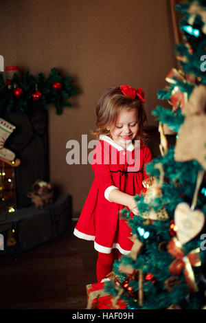 Ragazza permanente decorazioni mette a un albero di Natale. Ind verticale Foto Stock