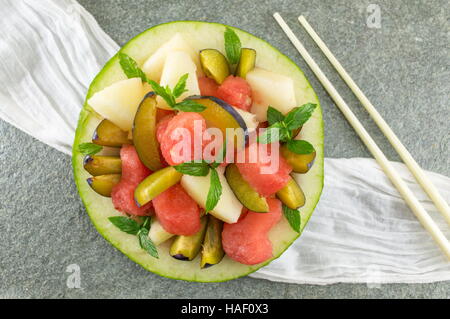 Macedonia di frutta fresca servita in un melone con heartshaped watermellon fette Foto Stock