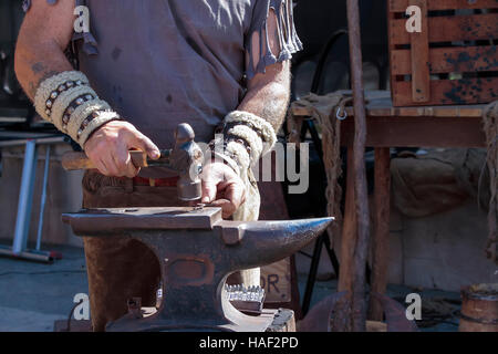 Primo piano delle mani di un fabbro lavora sull'incudine Foto Stock