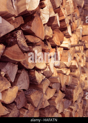 Legna da ardere impilata in alimentazione calda luce del tramonto texture di sfondo Foto Stock