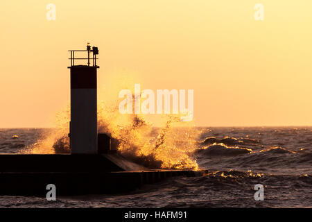 Basked in mattina presto luce dell'alba, onde schiantarsi su piloni a Port Stanley Ontario, Canada, lungo la riva del Lago Erie. Foto Stock