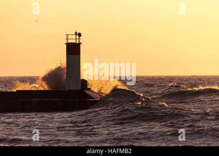 Basked in mattina presto luce dell'alba, onde schiantarsi su piloni a Port Stanley Ontario, Canada, lungo la riva del Lago Erie. Foto Stock