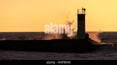 Basked in mattina presto luce dell'alba, onde schiantarsi su piloni a Port Stanley Ontario, Canada, lungo la riva del Lago Erie. Foto Stock