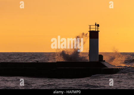 Basked in mattina presto luce dell'alba, onde schiantarsi su piloni a Port Stanley Ontario, Canada, lungo la riva del Lago Erie. Foto Stock