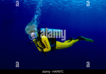 Donna bionda che indossa un giallo muta subacquea nel mare blu, Mar Rosso, Egitto Foto Stock