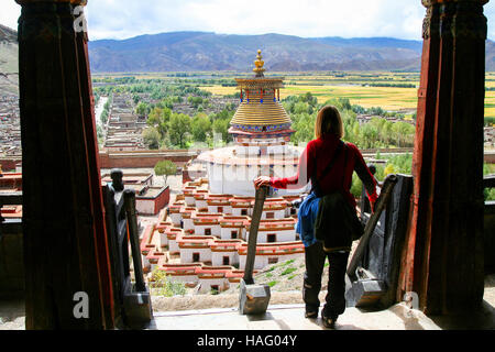 Viaggiatore femmina in piedi in cima alle scale di un monastero guardando il buddista Kumbum chorten Gyantse in città, nella regione autonoma del Tibet di ch Foto Stock