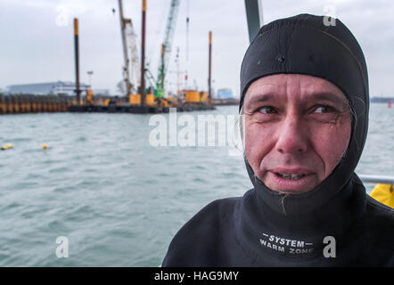 Wismar in Germania. 30 Novembre, 2016. Il Research Diver Dirk Hering sorge sulla piattaforma di lavoro dopo il recupero di un pezzo di legno da un incastro a dente medievale che era stato recuperato dal porto di Wismar, Germania, 30 novembre 2016. Gli archeologi hanno iniziato la scopertura medievale due relitti del Mar Baltico, accompagnato dal maltempo. Le navi erano risalenti al XIII e XIV secolo mediante analisi della recuperati frammenti di legno. Foto: Jens Büttner/dpa-Zentralbild/dpa/Alamy Live News Foto Stock