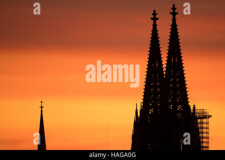 Colonia, Germania. 30 Novembre, 2016. La doppia guglie del duomo di Colonia può essere visto come ombre giganti contro un cielo arancione durante il tramonto a Colonia, Germania, 30 novembre 2016. Foto: Marius Becker/dpa/Alamy Live News Foto Stock