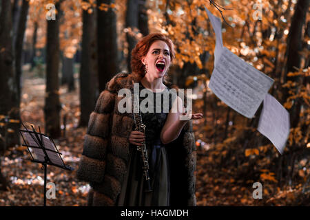 Giovane donna emotiva a buttare via i fogli musicali e di trattenimento di un oboe in mano Foto Stock