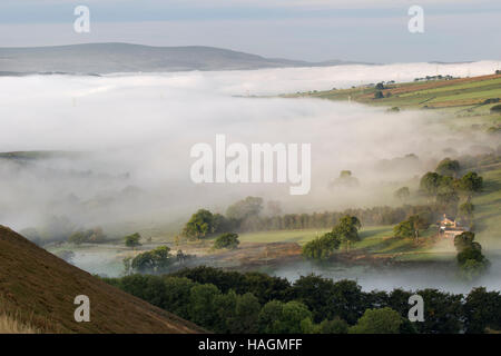 La vista da Barcombe Hill, sede di un forte collinare dell'età del ferro e della Long Stone, con la bassa nebbia aggrappata alla valle del South Tyne Foto Stock