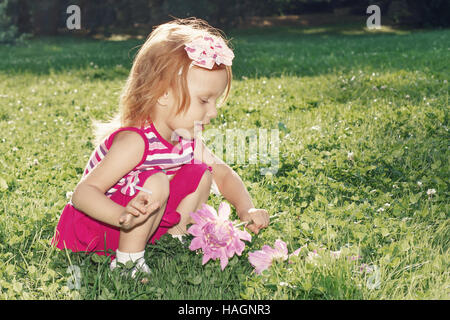 La ragazza con i capelli rossi a giocare con fiori in natura Foto Stock