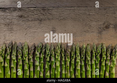 Piccole punte di asparagi su un tagliere di legno Foto Stock