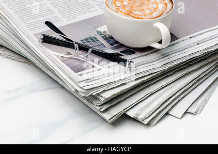 Pila di giornale,tazza di caffè e di lenti sulla tavola. Foto Stock