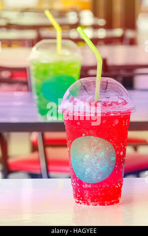 Soft drink in bicchieri di plastica sul tavolo,rosso colore caldo. Foto Stock