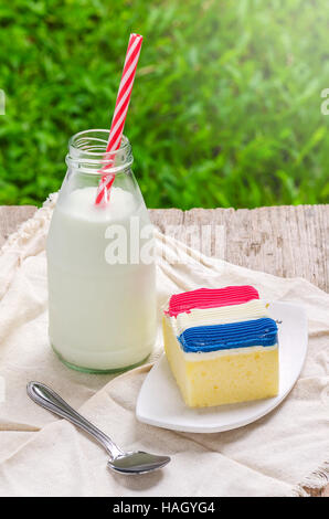 Pezzo di torta topping Francia bandiera colore(blu bianco e rosso) crema e bottiglia di latte fresco su un tavolo di legno. Foto Stock