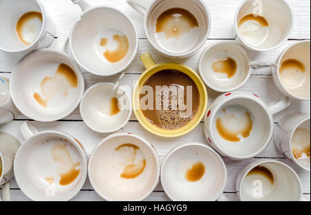 Giallo tazza di caffè nel mezzo del bicchiere sporco su sfondo in legno.Vista dall'alto. Foto Stock