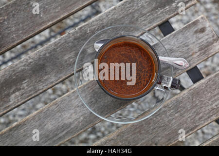 Bagno turco preparato di fresco terreno naturale, caffè schiuma marrone schiuma in vetro trasparente tazza con piattino su vintage tavolo in legno, close up, elevati top Foto Stock