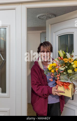 Senior lady accettando una consegna fiori sulle madri di giorno o di compleanno. Foto Stock