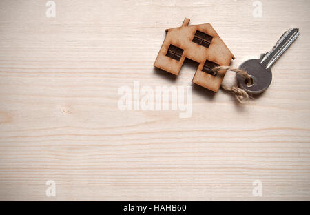 Piccola casa fissata ad un tasto su un sfondo di legno con spazio per il testo Foto Stock