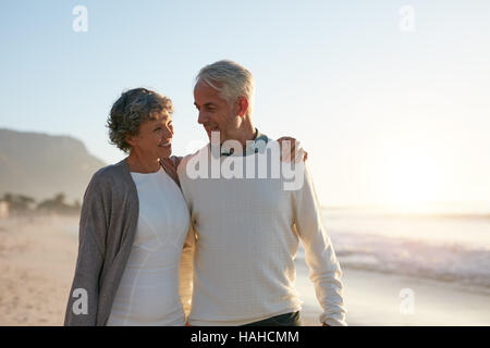 Colpo all'aperto di amorevole coppia senior avente una passeggiata sulla spiaggia al tramonto. Foto Stock
