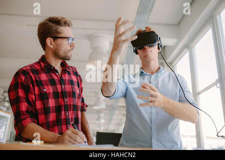 Colpo di due giovani uomini test di realtà virtuale auricolare. Gli uomini d' affari discutendo e test occhiali VR. Foto Stock