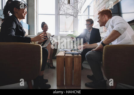 La gente di affari nella lobby e seduti attorno a un tavolo e discutere la strategia aziendale. Imprenditori e imprenditrici riunione in ufficio moderno. Foto Stock