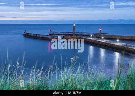 Vista su Whitby pontili e ingresso del porto al tramonto. Whitby, North Yorkshire, Inghilterra. Regno Unito Foto Stock