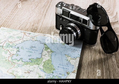 Vecchia macchina fotografica su una mappa di laghi in Polonia. Fotocamera obsoleta su una mappa. Occhiali da sole nei pressi della vecchia telecamera. Foto di sbianca Foto Stock