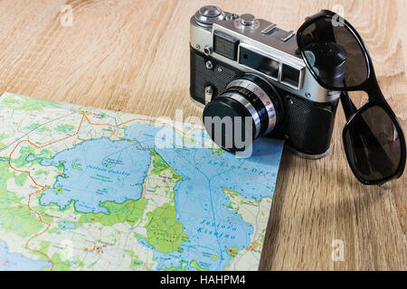 Vecchia macchina fotografica su una mappa di laghi in Polonia. Fotocamera obsoleta su una mappa. Occhiali da sole nei pressi della vecchia telecamera. Foto Stock