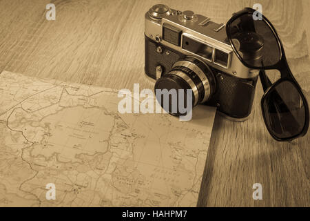 Vecchia macchina fotografica su una mappa di laghi in Polonia. Fotocamera obsoleta su una mappa. Occhiali da sole nei pressi della vecchia telecamera. Foto seppia Foto Stock