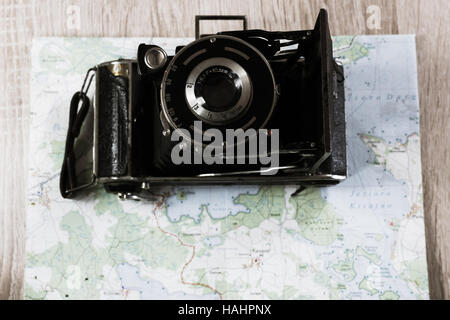 Vecchio piegato Leica fotocamera con lente prontor su una mappa di laghi in Polonia. Fotocamera obsoleta su una mappa. Foto Stock