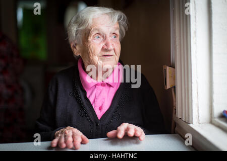 Donna anziana sorpreso guarda fuori della finestra. Foto Stock