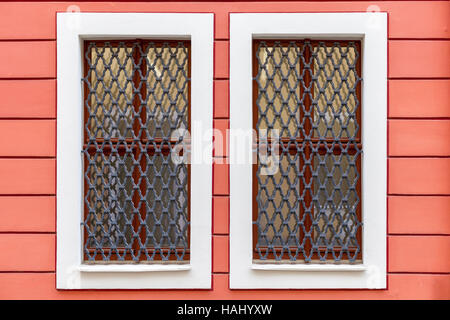 Una finestra nel tenement house su una pianta ornamentale parete rossa. Foto Stock