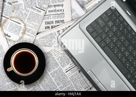 Il luogo di lavoro con computer portatile e tazza di caffè su sfondo di giornale Foto Stock