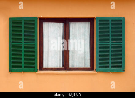 Apre la finestra verde tapparelle su casa gialla facciata Foto Stock