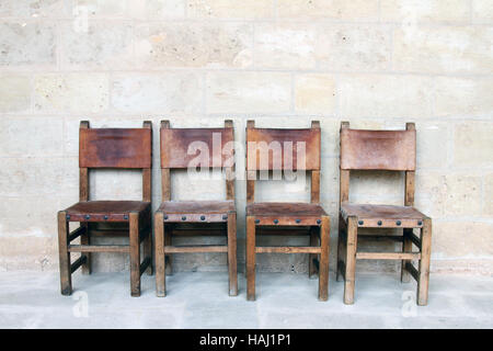 Quattro sedie vintage presso il muro di pietra Foto Stock