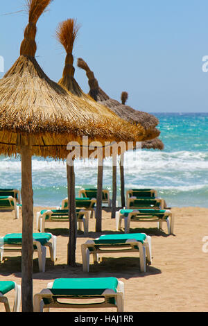 Lettini e ombrelloni di paglia sulla spiaggia Foto Stock
