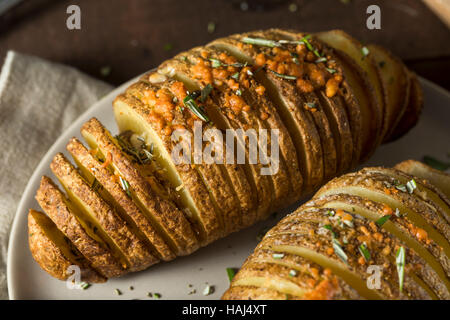 In casa Cheesy Hasselback patate con erbe fresche Foto Stock