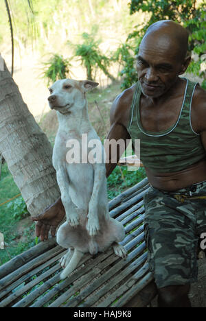 Un contadino con il suo cane nella sua le risaie, Lawigan, San Joaquin, Iloilo, Filippine. Foto Stock