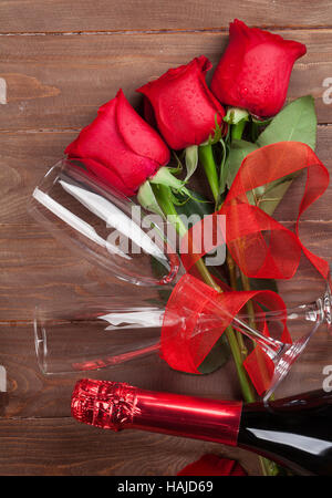 Rose rosse e champagne su sfondo di legno. Vista superiore Foto Stock