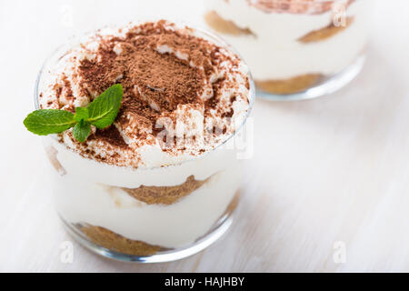 In casa il tiramisù dessert in vetro bianco sul tavolo di legno Foto Stock