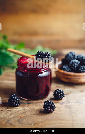 Freschi Fatti in casa marmellata di blackberry in un barattolo di vetro su uno sfondo di legno Foto Stock