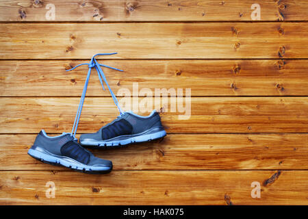 Coppia di scarpe sportive appendere su un chiodo su un marrone parete in legno Foto Stock