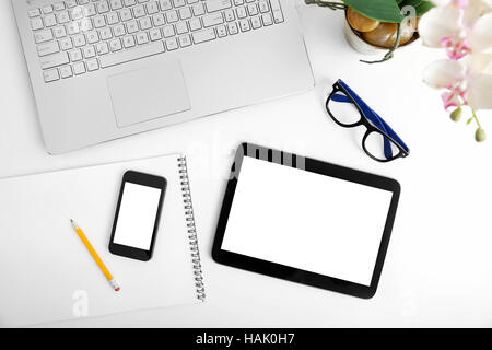 Area di lavoro con computer portatile, vuoto digital tablet e smartphone sul tavolo bianco Foto Stock